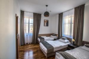 a hotel room with three beds and windows at Hotel Sukcesor in Zamość