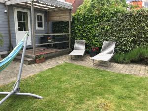two white chairs and a hammock in a yard at Bungalow De Perenboom in Westkapelle