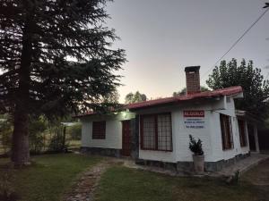 ein kleines weißes Haus mit einem Baum im Hof in der Unterkunft Cabañas Pequeño Paraíso in Tunuyán