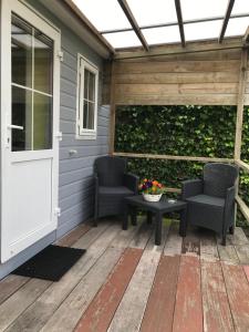 een patio met 2 stoelen, een tafel en een deur bij Bungalow De Perenboom in Westkapelle