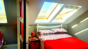 1 dormitorio con tragaluces y 1 cama con sábanas rojas en Sona Baile Home Stay, en Dooagh