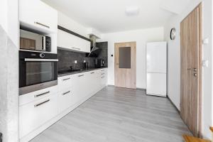 cocina con armarios blancos y nevera blanca en Apartmán Jasmin, en Frymburk