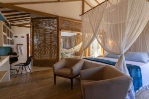 a bedroom with a bed and a chair and a desk at Casa Nuhatê Trancoso - Praia do Espelho in Praia do Espelho