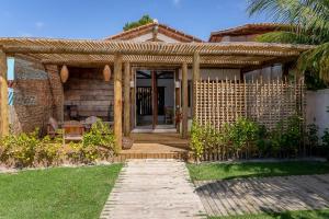 a brick house with a wooden pergola at Casa Nuhatê Trancoso - Praia do Espelho in Praia do Espelho