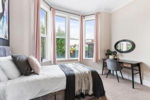 Schlafzimmer mit einem Bett, einem Schreibtisch und Fenstern in der Unterkunft Exquisite Flat - Parking - Sleeps 9 in Bristol