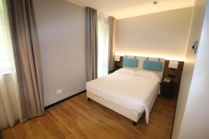 um quarto com uma cama branca e uma cabeceira azul em Hotel Domenichino em Milão