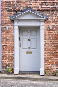 a white front door of a brick building at The Barth Room at Cheshire Boutique Barns in Nantwich