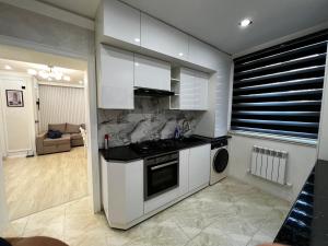 a kitchen with white cabinets and a stove at Entire Apartment in Central Nukus in Nukus +11 photos