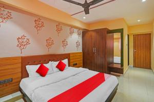 a bedroom with a large bed with red pillows at Flagship Hotel Happy Stay in Surat