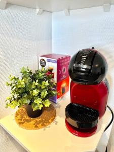 une cafetière rouge et une plante sur une étagère dans l'établissement L’Esquile Rose - Charmant studio en hypercentre, à Toulouse
