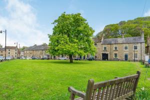 a park with a bench and a tree and buildings at Bay Tree Cottage in Richmond