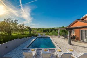 une piscine avec des chaises blanches et une maison dans l'établissement Villa Pendolina with pool and grill in Umag, à Buroli