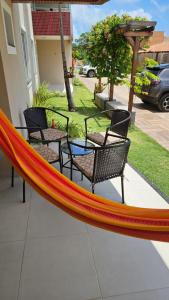 a hammock on a patio with chairs and a table at Cantinho do Atalaia à 650 metros da praia - Seu conforto fora de casa in Salinópolis