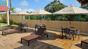 een patio met tafels, stoelen en parasols bij Cantinho do Atalaia à 650 metros da praia - Seu conforto fora de casa in Salinópolis