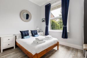Schlafzimmer mit einem Bett mit blauen Vorhängen und einem Fenster in der Unterkunft Swan Lake in Poole