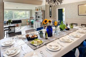 Una larga mesa blanca con platos y copas de vino. en The Elmfield, 8 Bed Villa with heated indoor Swimming Pool and Cocktail Bar, en Ilfracombe