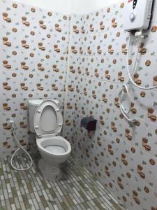a bathroom with a toilet in a room with a wall covered in cookies at Baan Fun Dee Chiang Khan in Chiang Khan