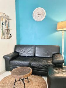 a black leather couch with a clock on a blue wall at La Pierre des Ducs in Matoury