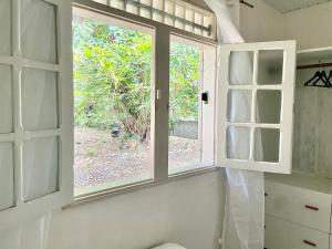 a window in a bathroom with a view of a garden at La Pierre des Ducs in Matoury