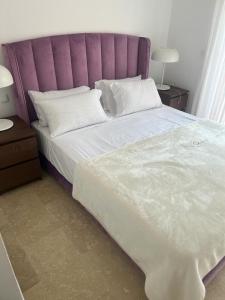 Schlafzimmer mit einem großen Bett mit einem lila Kopfteil in der Unterkunft Villa puerto banuus Marbella in Marbella