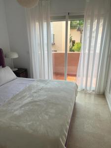 ein Schlafzimmer mit einem großen Bett und einem großen Fenster in der Unterkunft Villa puerto banuus Marbella in Marbella