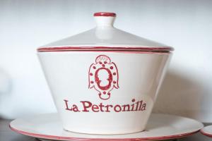 a white container with a red and white label on a plate at La Petronilla Appartamenti Montepetriolo in Monte Petriolo