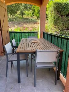 a wooden table and chairs sitting on a porch at Appartement piscine et vue mer. in Cavalaire-sur-Mer +2 photos