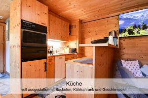 Cabaña con cocina con armarios de madera y TV. en Gemütliches Chalet mit schöner Aussicht en Küblis