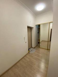 um quarto vazio com paredes brancas e piso de madeira em 1-комнатная квартира посуточно em Taldykolʼ