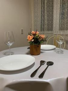 uma mesa com dois pratos e dois copos e um vaso com flores em 1-комнатная квартира посуточно em Taldykolʼ