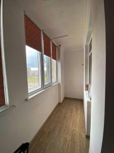 um quarto vazio com duas janelas e um piso de madeira em 1-комнатная квартира посуточно em Taldykolʼ