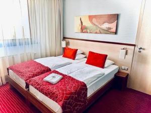 a hotel room with two beds with red pillows at Hotel Famulus in Győr