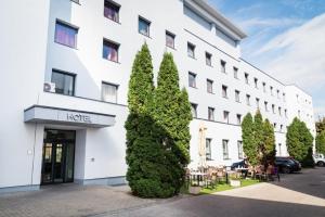 duży biały budynek z drzewami przed nim w obiekcie Hotel Famulus w Győr