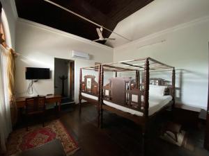 a bedroom with a four poster bed and a television at Ballard Bungallow in Cochin