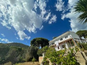 una casa en una colina con un cielo azul y nubes en Can Domenech Montnegre, en Tordera