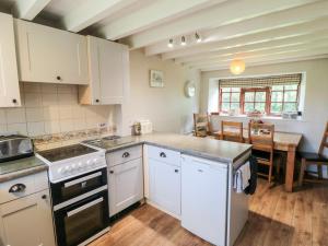 a kitchen with white cabinets and a dining room with a table at Holly Cottage in Whitby