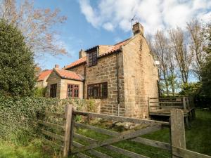 an old stone house with a fence in front of it at Holly Cottage in Whitby