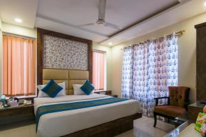 a bedroom with a bed and a chair and windows at Baba Residency - 5 Minutes from railway station in New Delhi