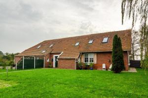 une maison en briques avec une pelouse verte devant elle dans l'établissement Huus an´t Koornfeld Dachgeschoss, à Osteel