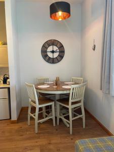 a dining room table with chairs and a clock on the wall at Stylish One bed apartment in Inverness