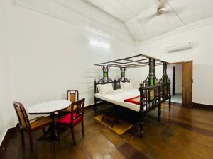 um quarto com uma cama, uma mesa e cadeiras em Ballard Bungallow em Cochin