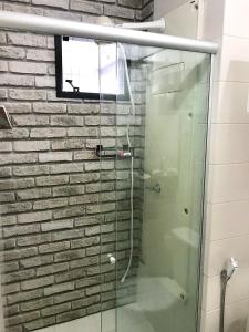 uma cabina de duche em vidro numa casa de banho com uma parede de tijolos em Mobiliado e aconchegante em Belém