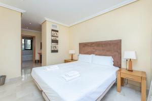1 Schlafzimmer mit einem großen weißen Bett und 2 Tischen in der Unterkunft Spacious Apartment with Views, Pools + Spa RDR346 in Estepona