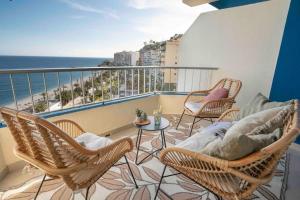 a balcony with chairs and a table and the ocean at Almuñecar Seawiews Deluxe SinEsedesignhomes in Almuñécar