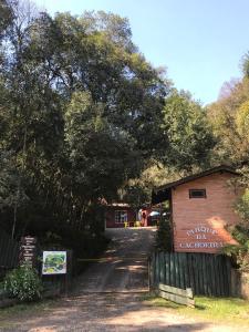 um edifício com uma placa ao lado de uma árvore em Pousada Parque da Cachoeira em São Francisco de Paula