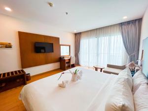 a hotel room with a large white bed and a television at Galina Hotel & Spa in Nha Trang