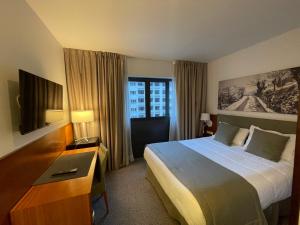 ein Hotelzimmer mit einem großen Bett und einem TV in der Unterkunft Zenit Diplomatic in Andorra la Vella