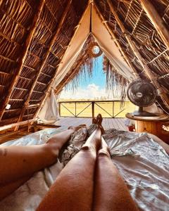 a person laying on a bed in a tent at Flor da Aldeia Eco Hospedaria in Camaçari