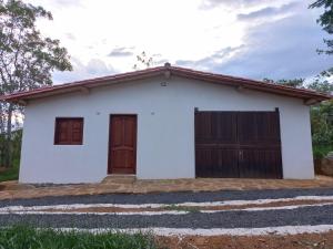Casa blanca con puertas marrones y garaje en CASA CAMPESTRE VILLA COVA Da IRIA BARICHARA, en Barichara