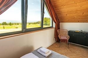 ein Schlafzimmer mit einem Bett, einem Fenster und einem Stuhl in der Unterkunft Białka i Skałka domki z balia i widokiem na góry in Białka Tatrzańska